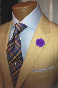 A man in a suit and tie with a purple flower pin.
