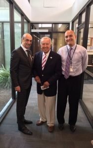 Three men standing in a hallway with one man holding something.