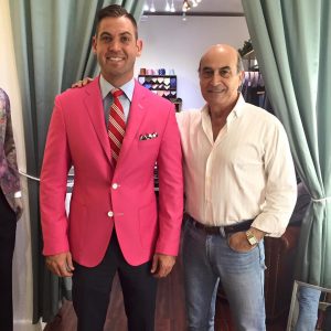A man in a pink suit and tie next to another man.