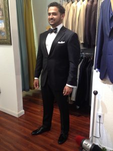 A man in a tuxedo standing next to a closet.