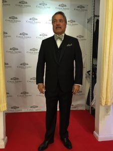 A man in a suit and tie standing on the red carpet.