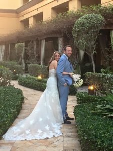 A man and woman posing for a picture in front of bushes.