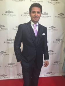 A man in a suit and tie standing on the red carpet.