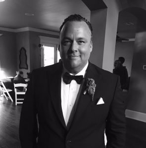 A man in a tuxedo standing next to a table.