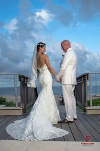 A bride and groom holding hands on the deck of their wedding.