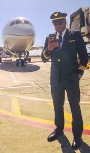 A man in uniform standing on the tarmac of an airport.