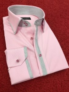 A pink shirt with green trim on the collar and cuffs.