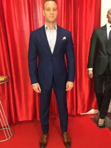 A man in a suit stands next to a wax figure.