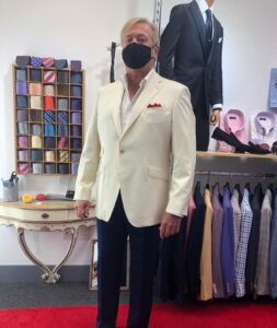 A man in a suit and mask standing next to a table.