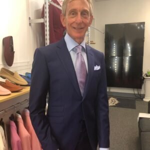 A man in a suit and tie standing next to a table.