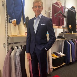 A man in a suit standing next to some racks of suits